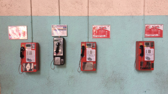 Four different phone boxes are mounted in slightly different heights on shabby turquoise wall